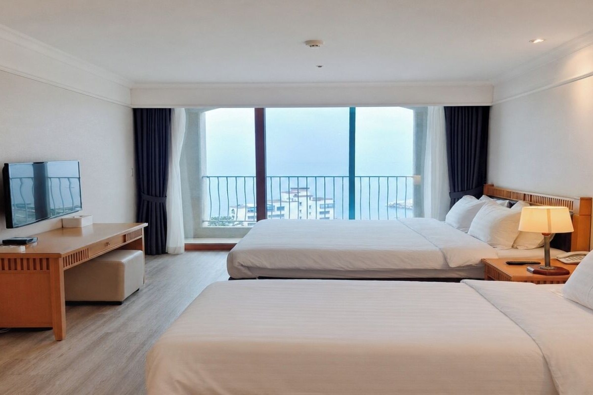 Une chambre d’hôtel avec deux lits, une télévision, un bureau et un balcon donnant sur la ville.