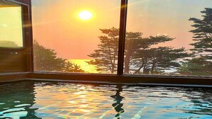 A room with a large window overlooking a body of water and a sunset.