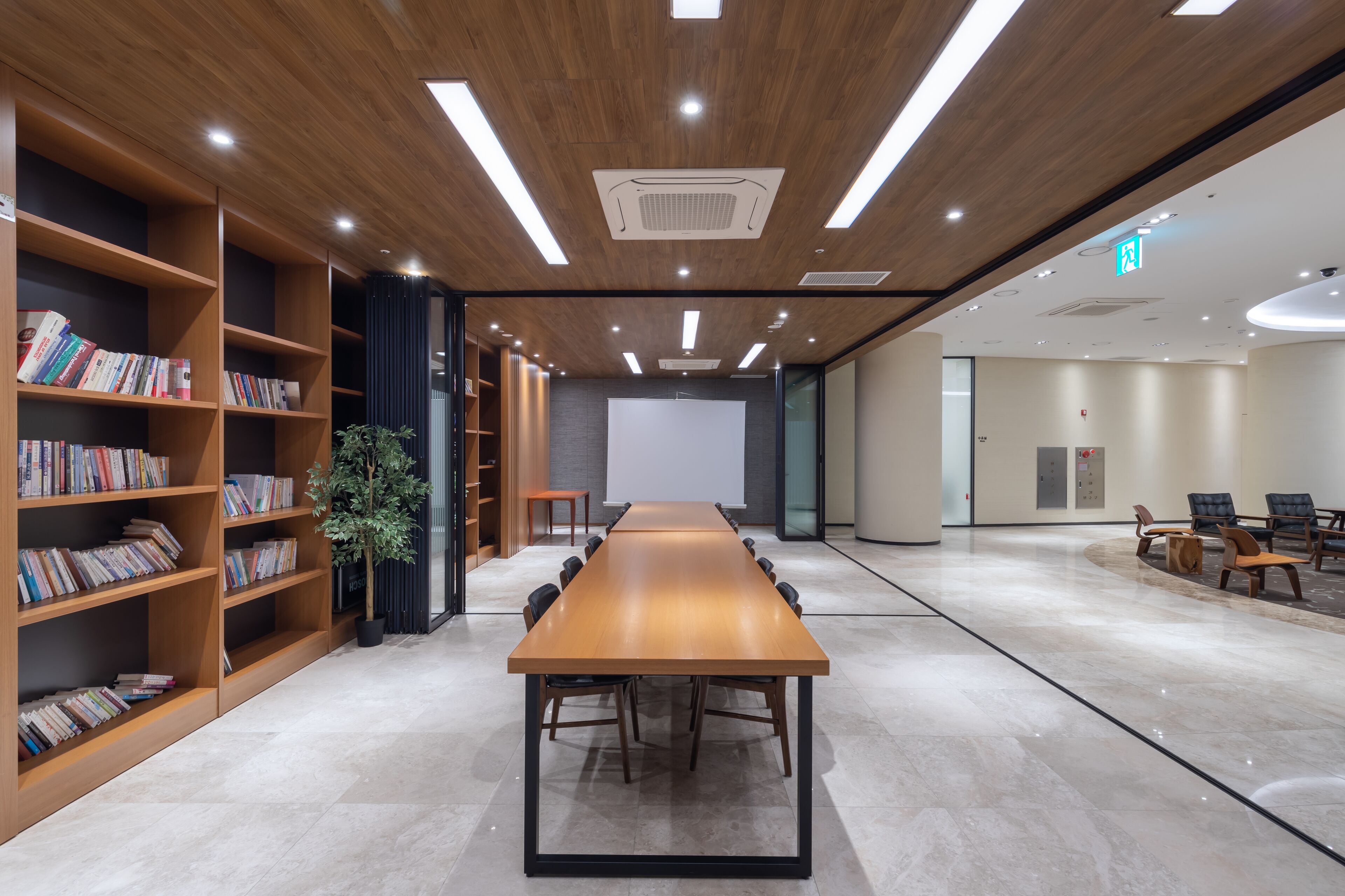 Una sala de conferències amb una taula llarga, cadires, una pantalla de projector i prestatgeries.