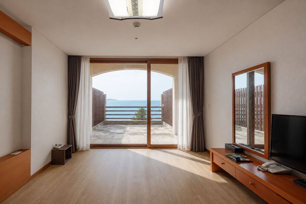 Ein Hotelzimmer mit einer großen Schiebetür, die auf einen Balkon mit Meerblick führt.