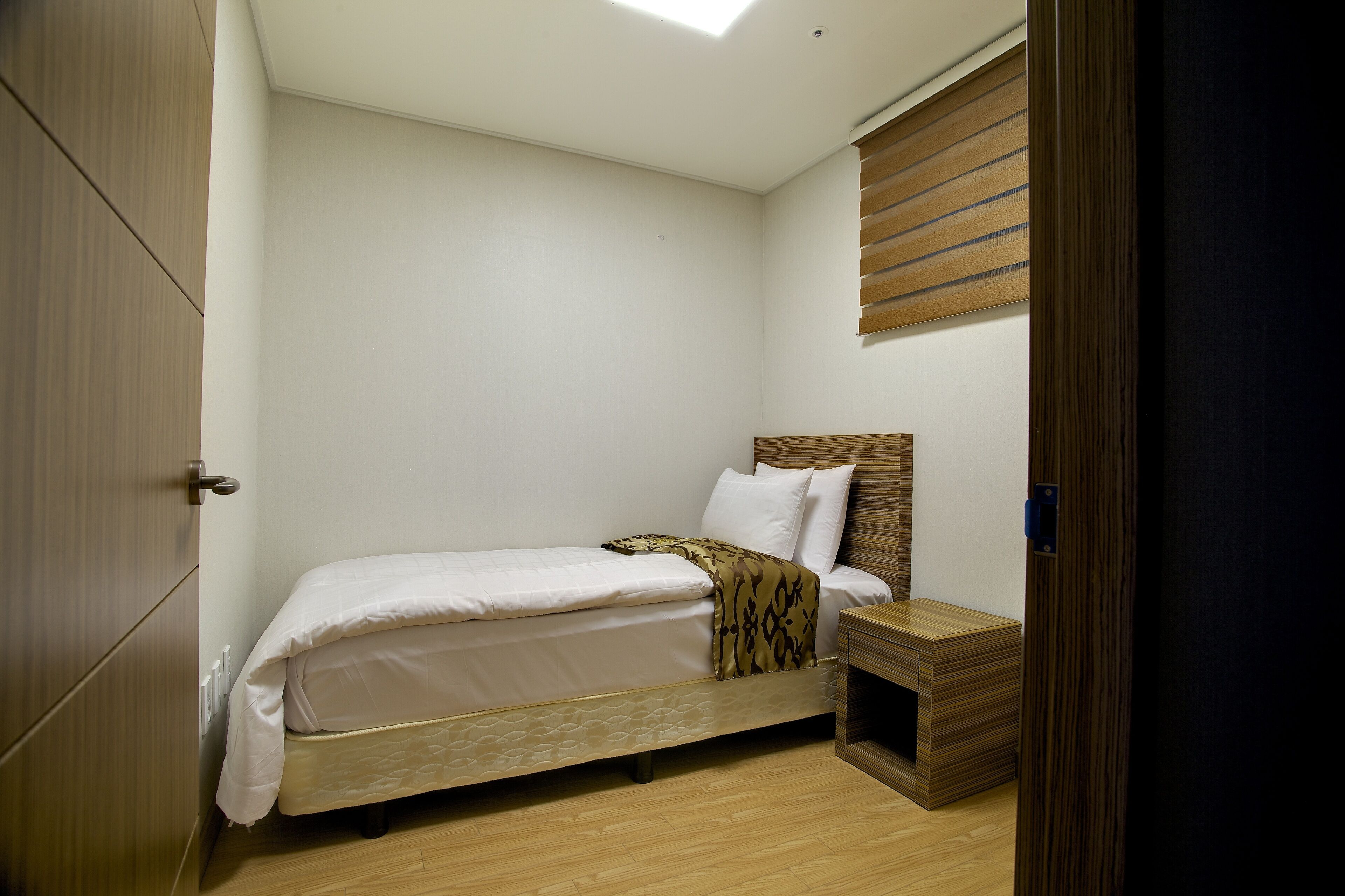 Un dormitorio con cama, armario de madera y mesita de noche.