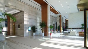 A spacious lobby with marble flooring, wooden accents, and potted plants. - The Class 300 (Sokcho)