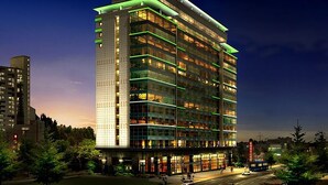 A multi-story hotel with a modern design, featuring a prominent glass facade and green lighting accents. - The Class 300 (Sokcho)