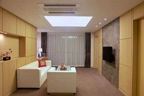 Suite junior, vista parcial al océano | Sala de estar | Televisión de pantalla plana 