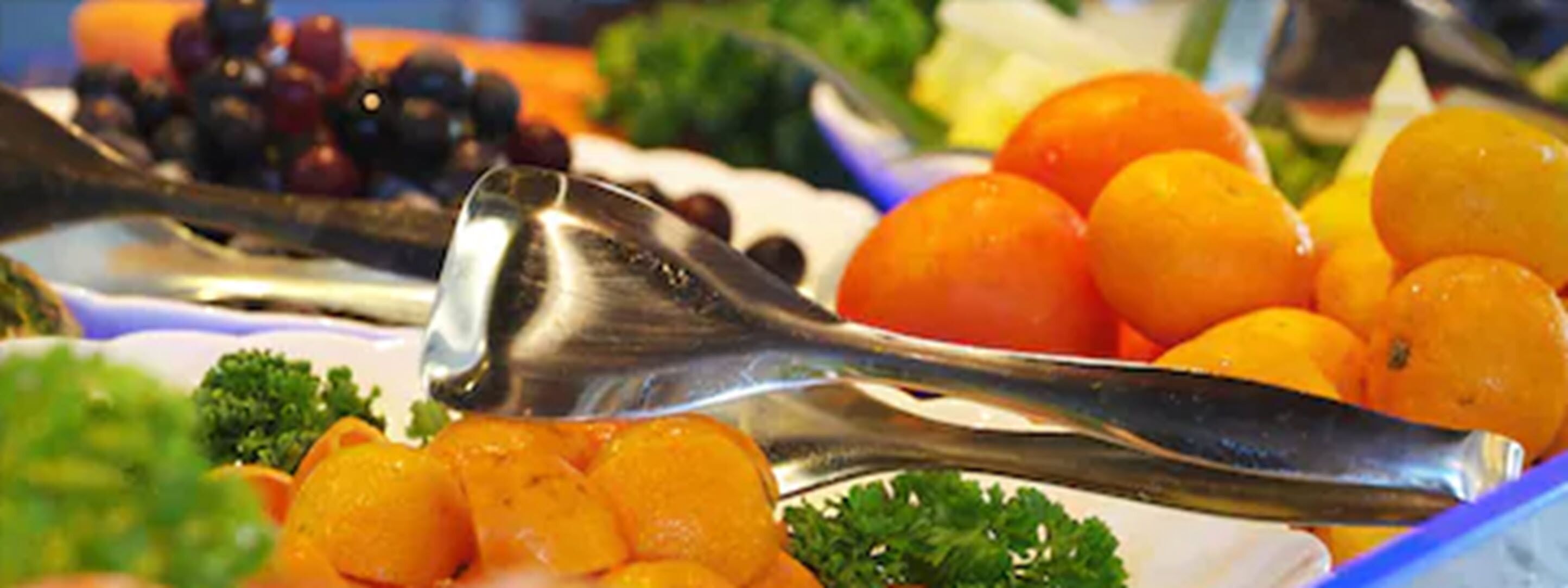 Ein Buffet mit verschiedenen Früchten und Gemüsesorten, darunter Orangen und Brokkoli.
