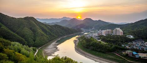 A river winding through a valley with mountains in the background and a small town with buildings along the riverbank.