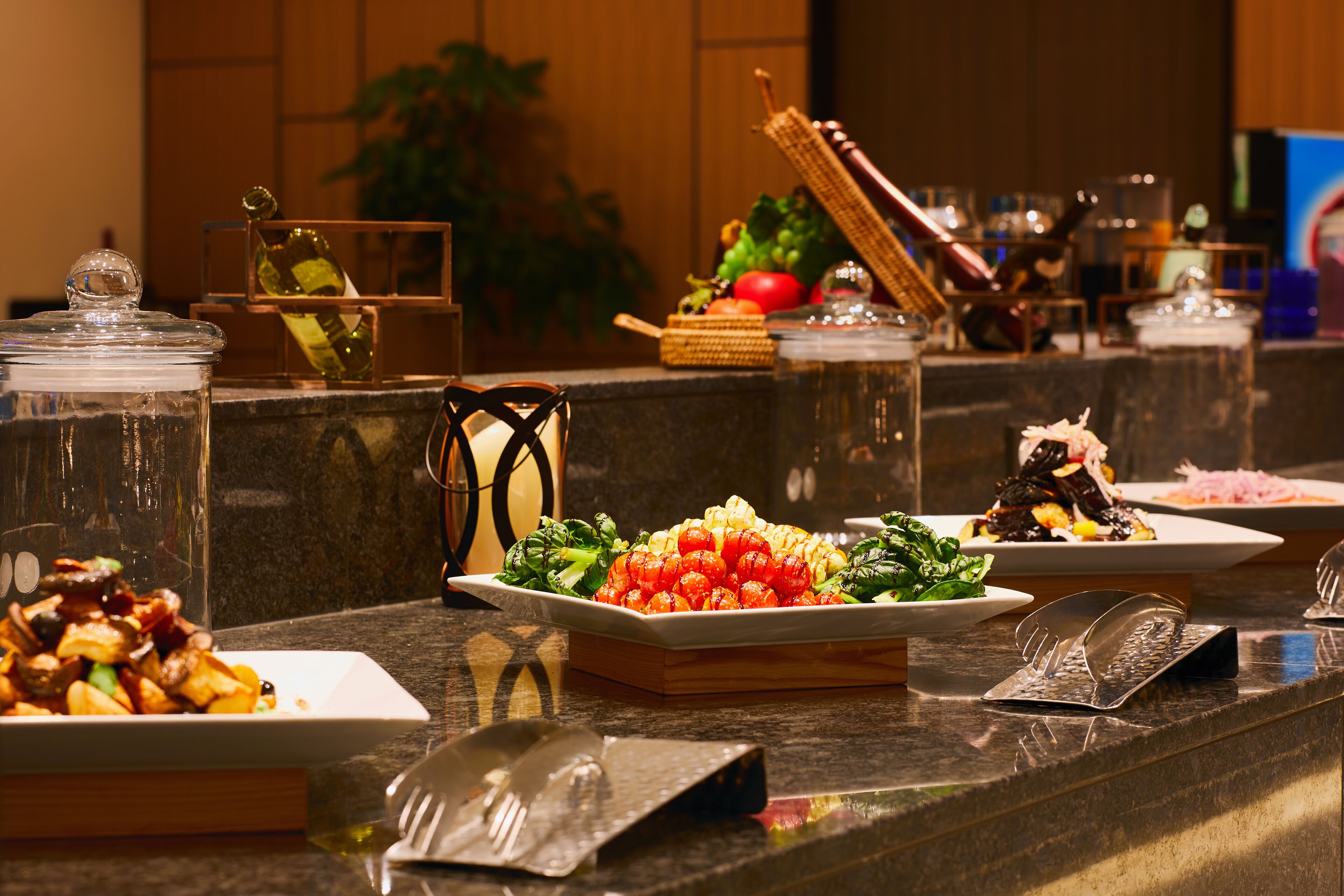 A buffet with various dishes, including salads and vegetables, arranged on a marble counter.