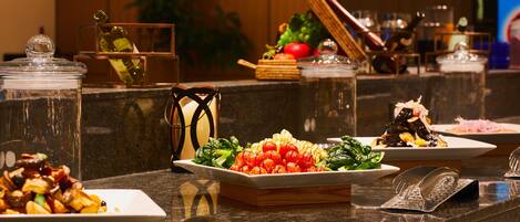A buffet with various dishes, including salads and vegetables, arranged on a marble counter.