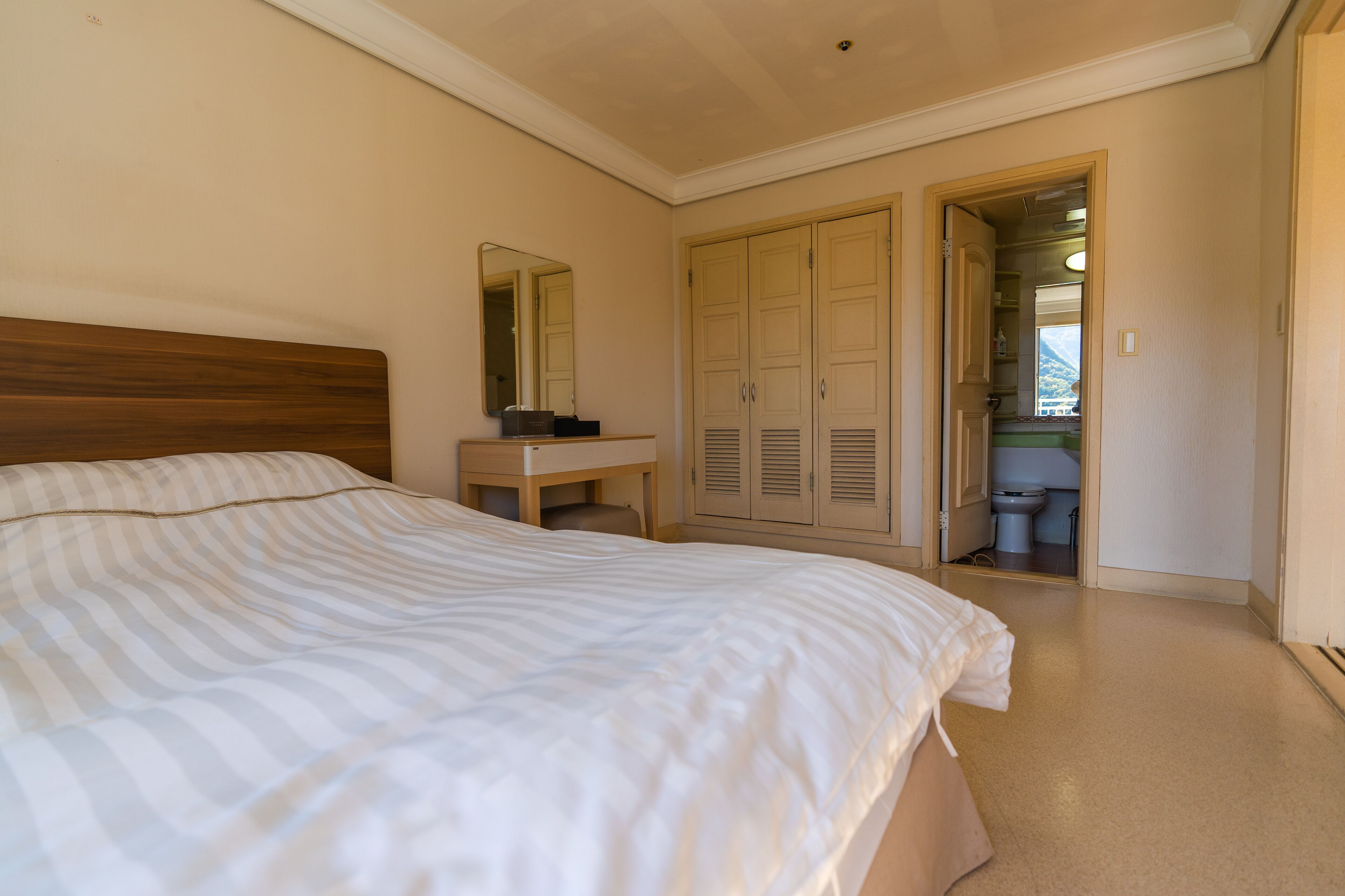 A bedroom with a bed, a bedside table, a mirror, and a wardrobe.