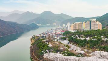 A coastal cityscape with a river, mountains, and a bridge.