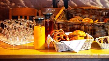 A breakfast table with glasses, orange juice, and pastries.