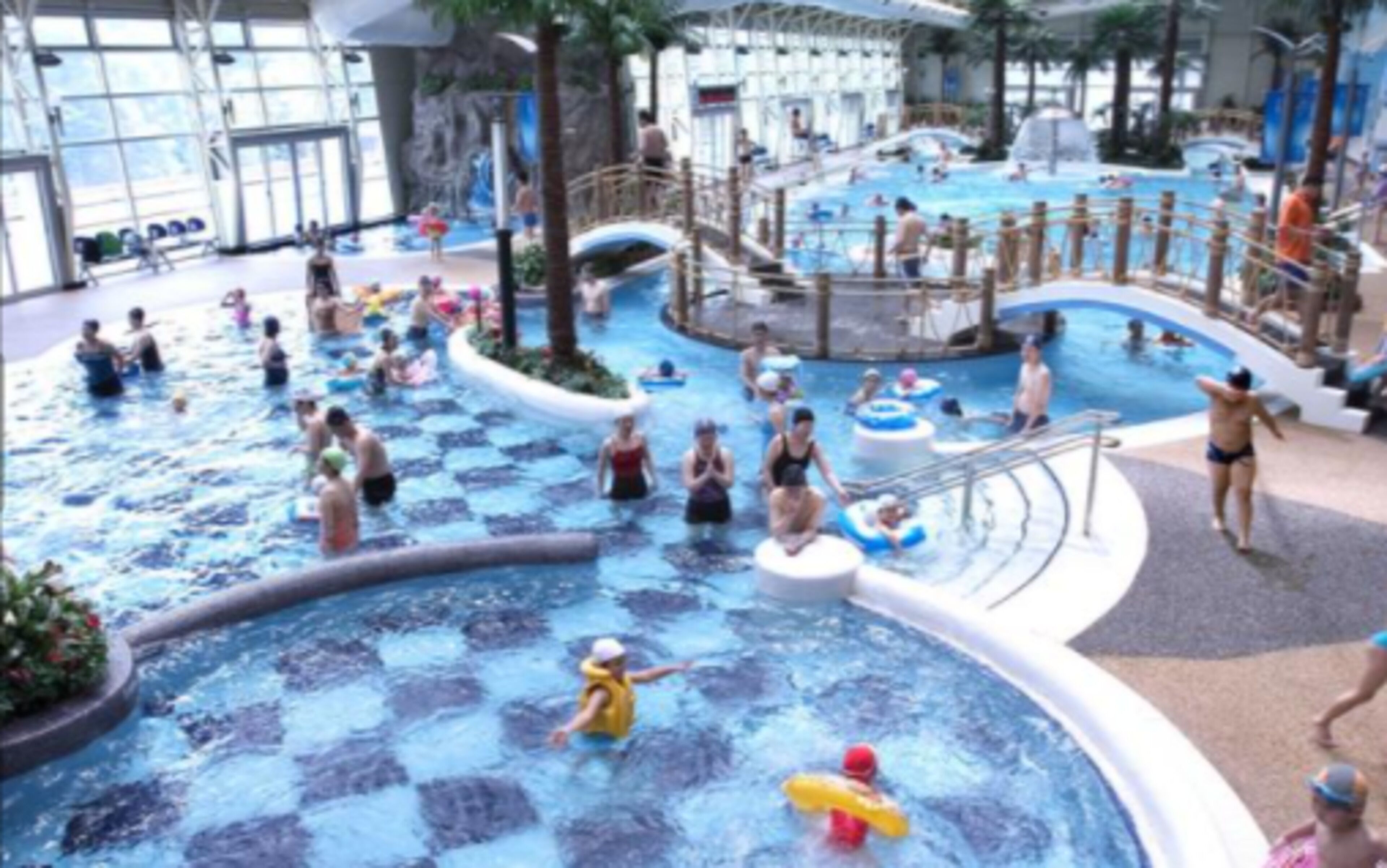 Un gran parque acuático interior con múltiples piscinas y toboganes.