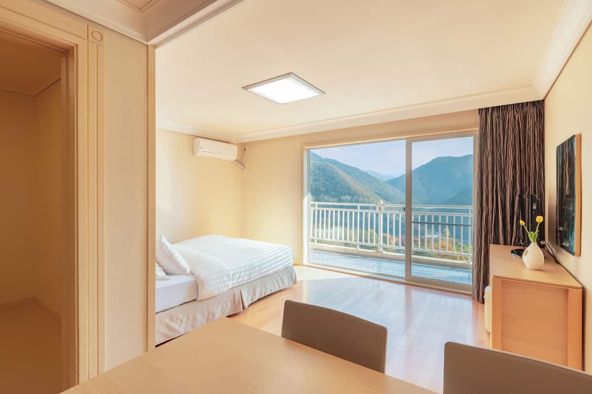 Une chambre d’hôtel avec un lit, une table et un balcon offrant une vue sur la montagne.