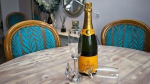 En flaske Veuve Clicquot champagne på et marmorbord med et glas og en vinåbner.