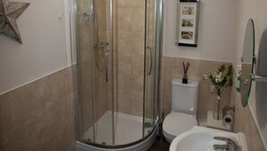 Et moderne badeværelse med en brusekabine med glasvægge, toilet, vask og et billede i ramme på væggen.