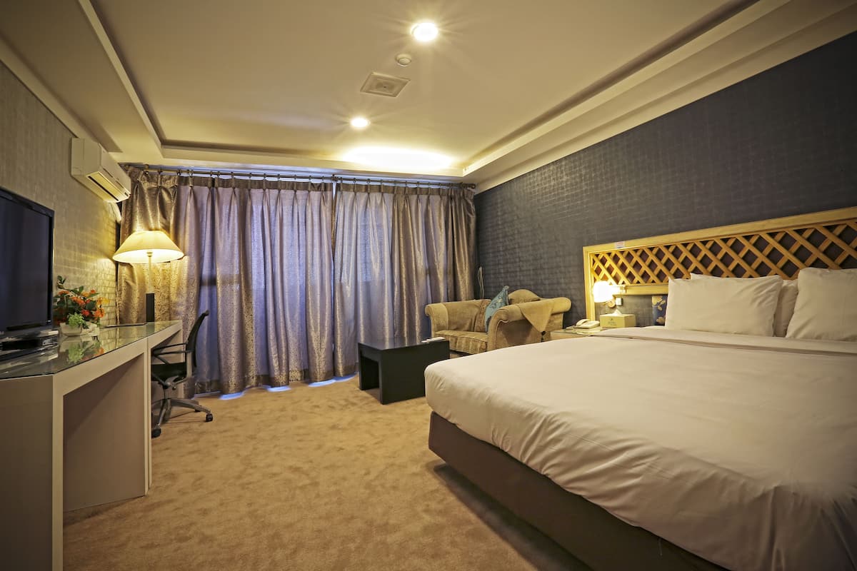 Une chambre d’hôtel avec un grand lit, un bureau avec un ordinateur, une chaise et une télévision.
