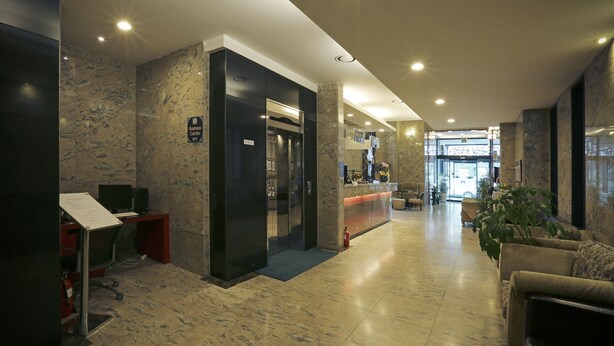 A modern lobby with a reception desk, a fire extinguisher, and a seating area with a plant. - Metro Tourist Hotel (Cheonan)