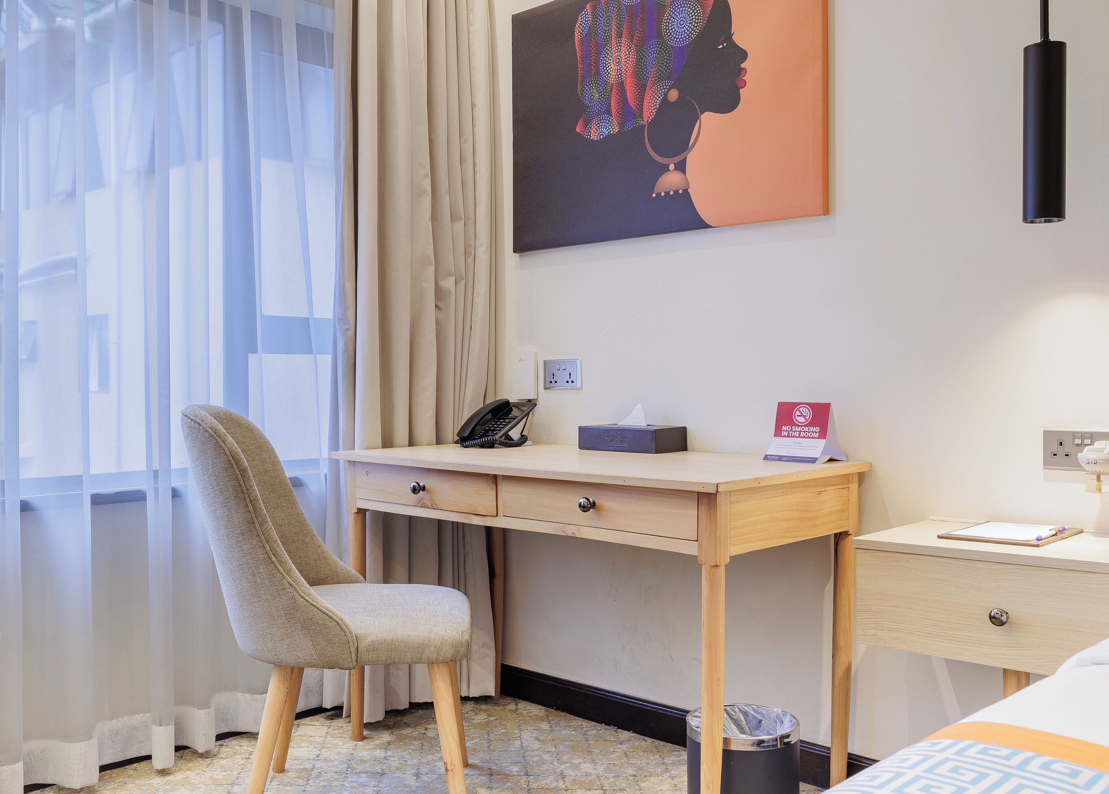 Habitación de hotel con escritorio, silla, cama y un cuadro en la pared.