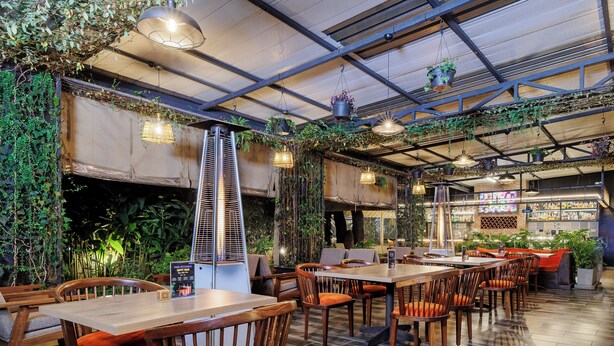 A restaurant with wooden tables and chairs, hanging plants, and a visible menu board. - PrideInn Westlands Luxury Boutique Hotel (Nairobi)