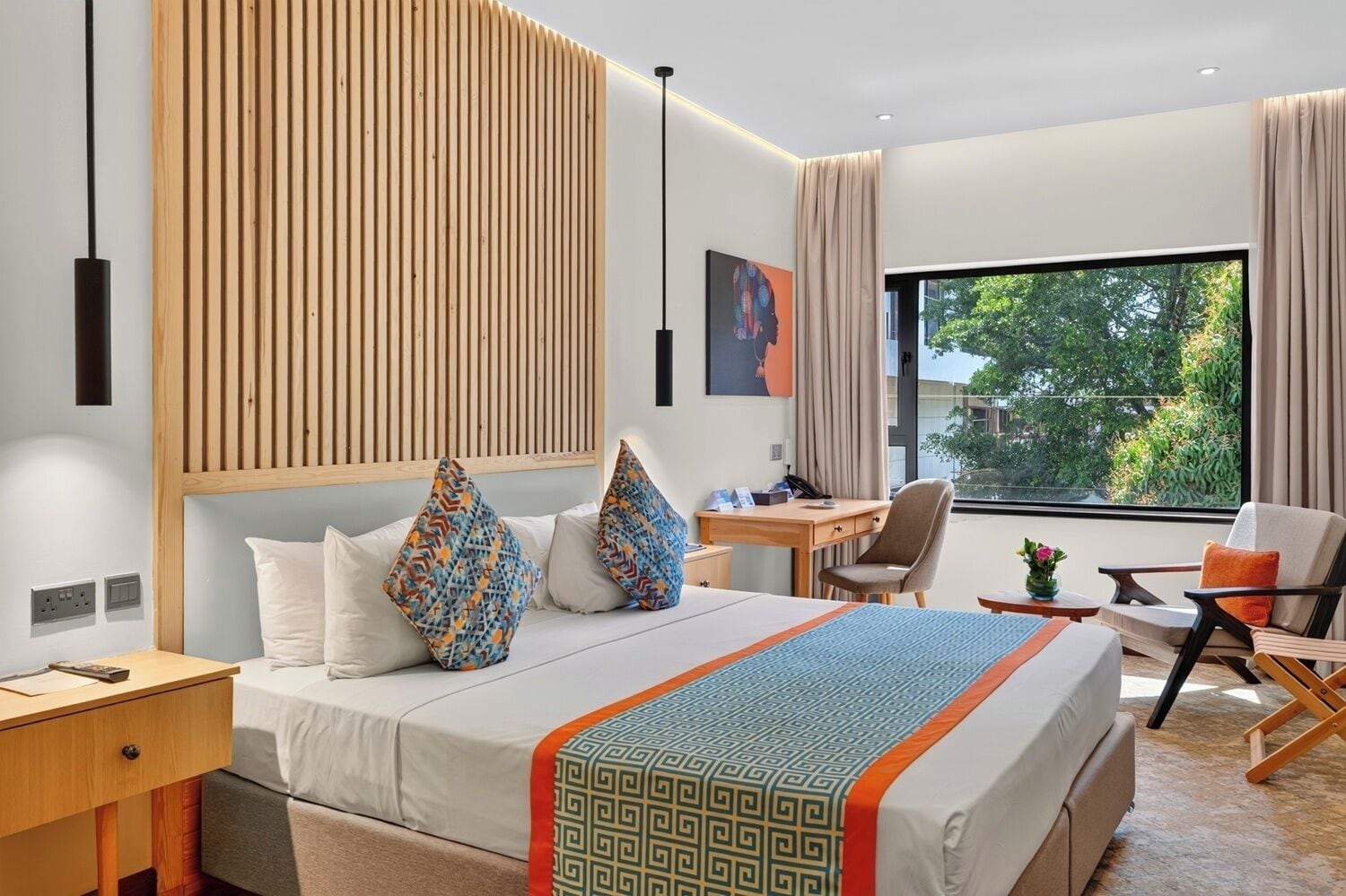 A hotel room with a bed, desk, chair, and large window.