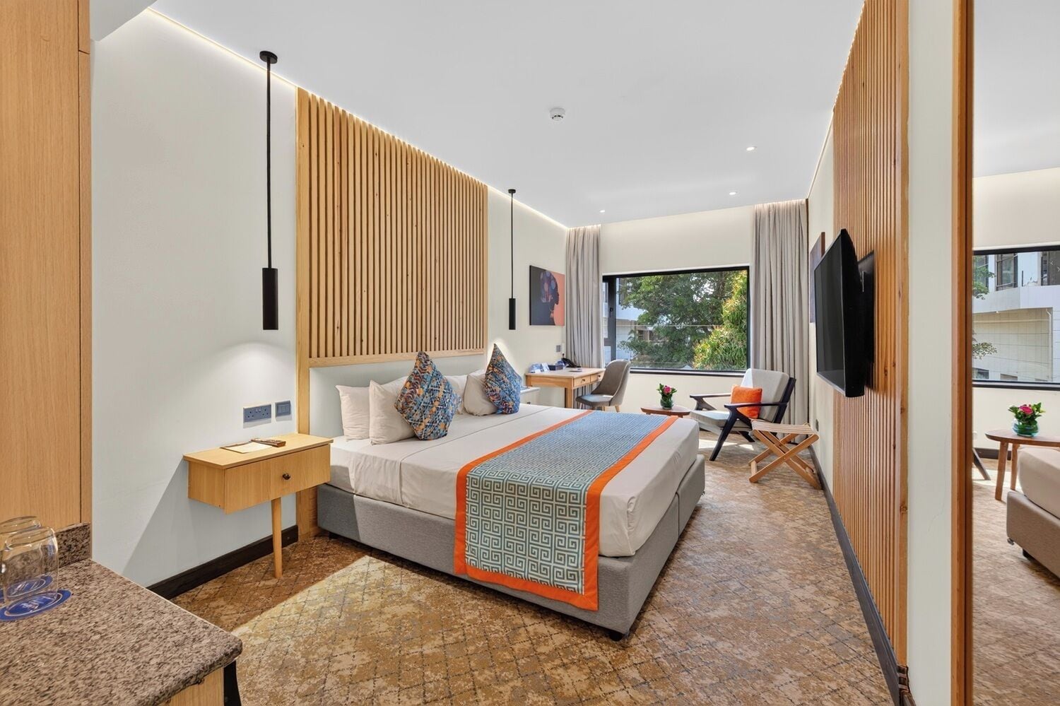 Una habitación de hotel moderna con una cama grande, un escritorio, una silla, un televisor y una ventana con vistas.