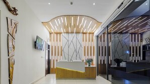 A modern reception area with a wooden reception desk, a flat-screen TV, and a decorative wall with geometric patterns. - PrideInn Westlands Luxury Boutique Hotel (Nairobi)