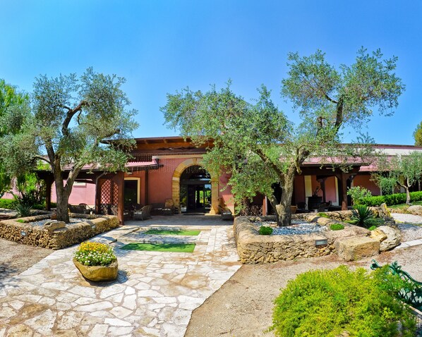A courtyard with stone flooring, a pergola, and a building entrance.