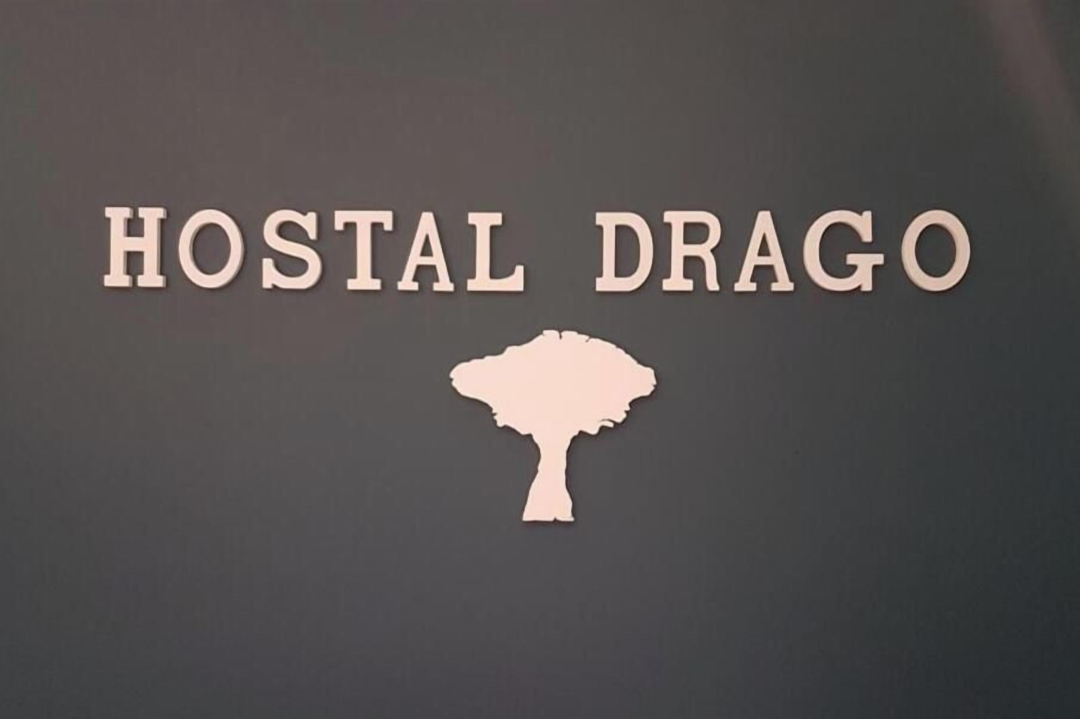 Un letrero con el texto 'HOSTAL DRAGO' y una silueta de un árbol.