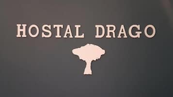 Un letrero con el texto 'HOSTAL DRAGO' y una silueta de un árbol.