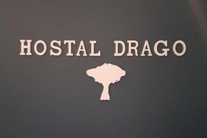 A sign with the text 'HOSTAL DRAGO' and a silhouette of a tree.