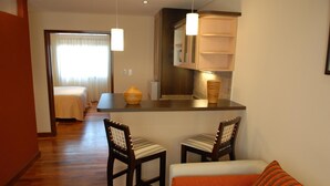 Un espacio habitable compacto con kitchenette, dos sillas de madera, un sofá y un comedor.