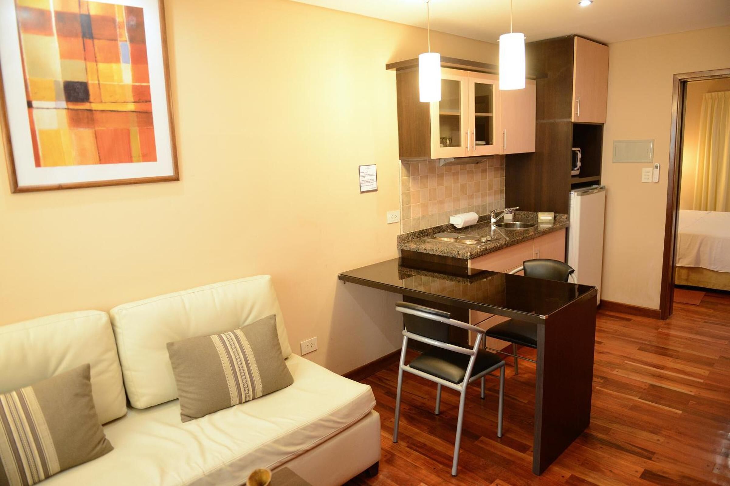 Un espacio habitable compacto con kitchenette, zona de comedor y sofá con cojines.