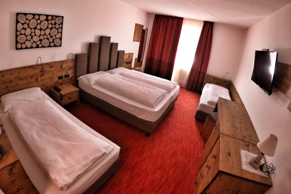 Habitación de hotel con dos camas, un cabecero de madera, un televisor de pantalla plana, un escritorio con lámpara y una alfombra roja.