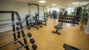 A gym with various exercise equipment, including dumbbells, a bench, and weight machines.