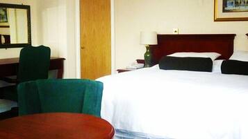 Una habitación de hotel con cama, escritorio, silla y mesita de noche.