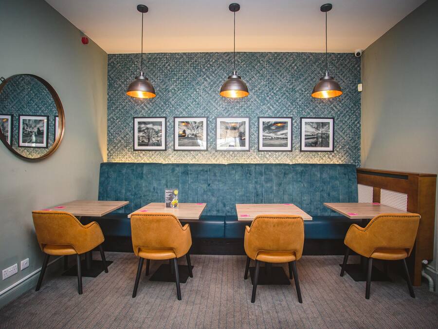 Ein Restaurant mit blauen Sitzbänken, Holztischen und orangefarbenen Stühlen.