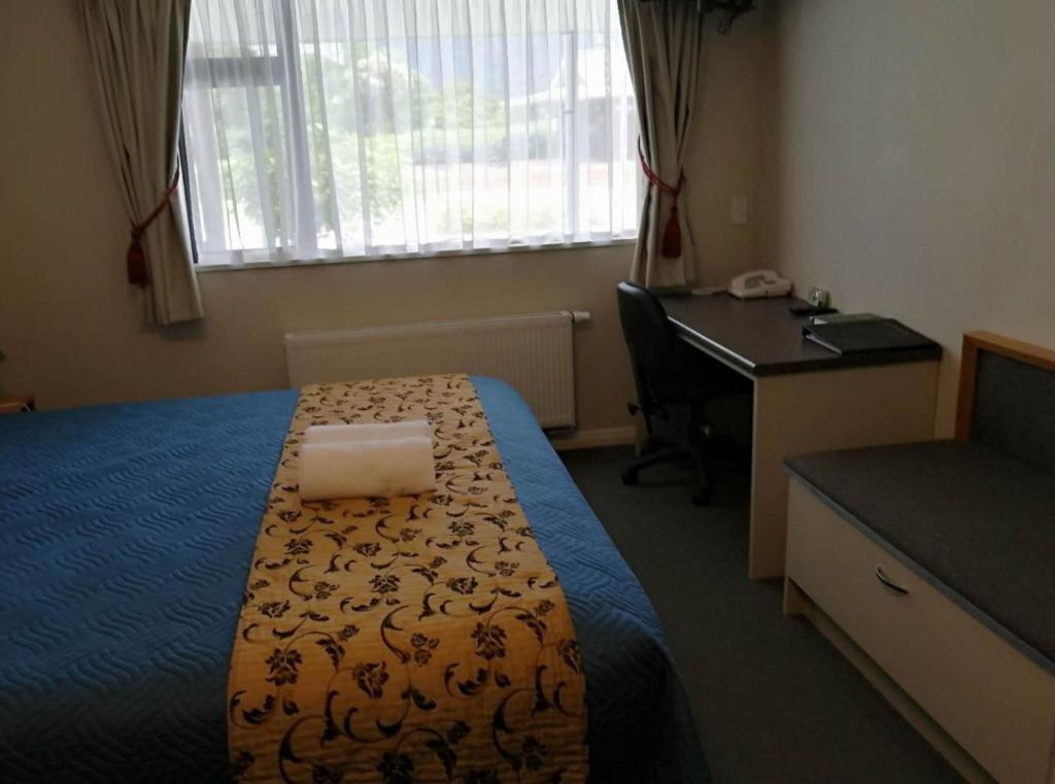 Quarto de hotel com cama, escrivaninha, cadeira e um pequeno sofá.