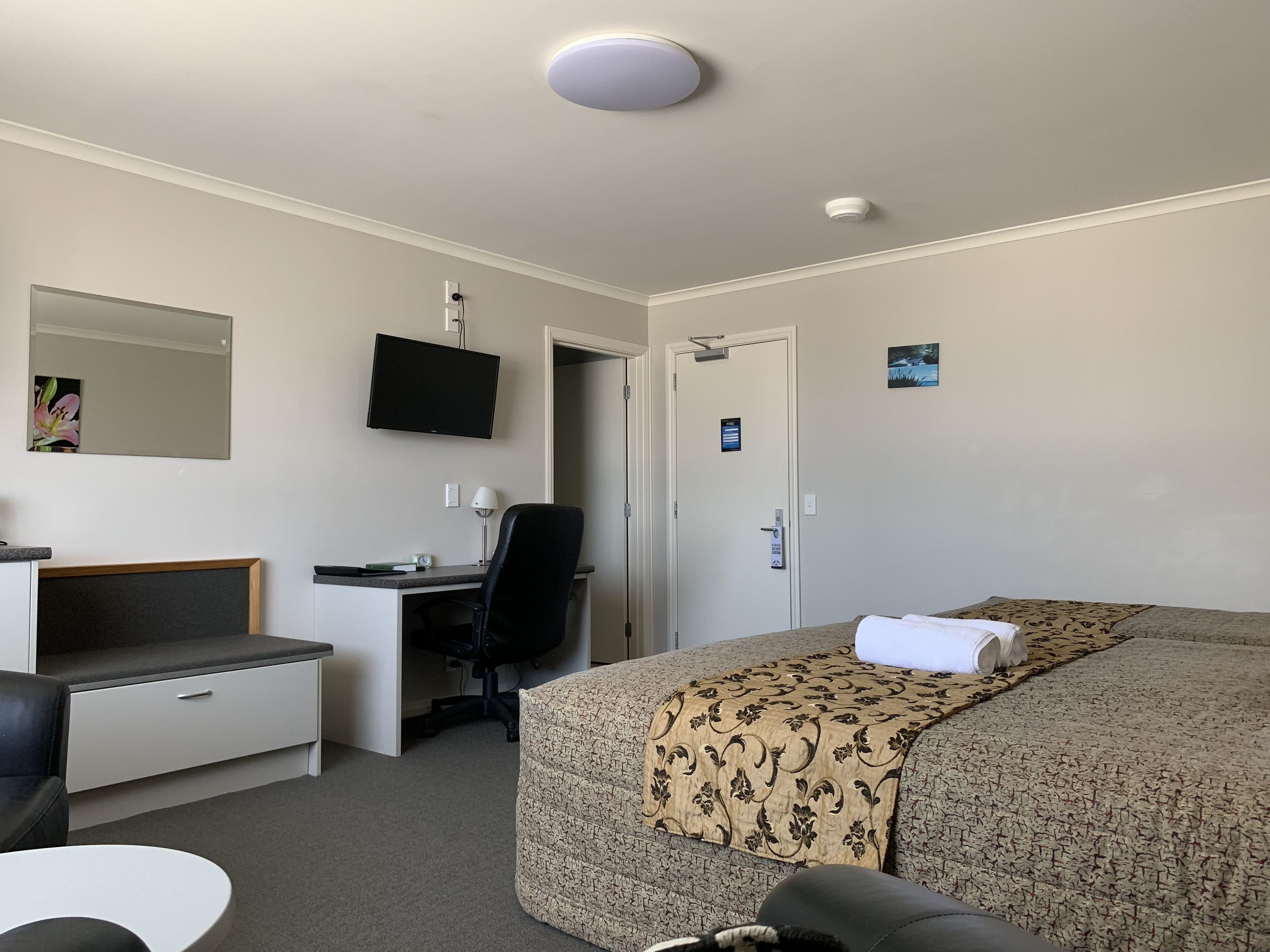 Una habitación de hotel con una cama, un escritorio con una silla, una televisión y una puerta.