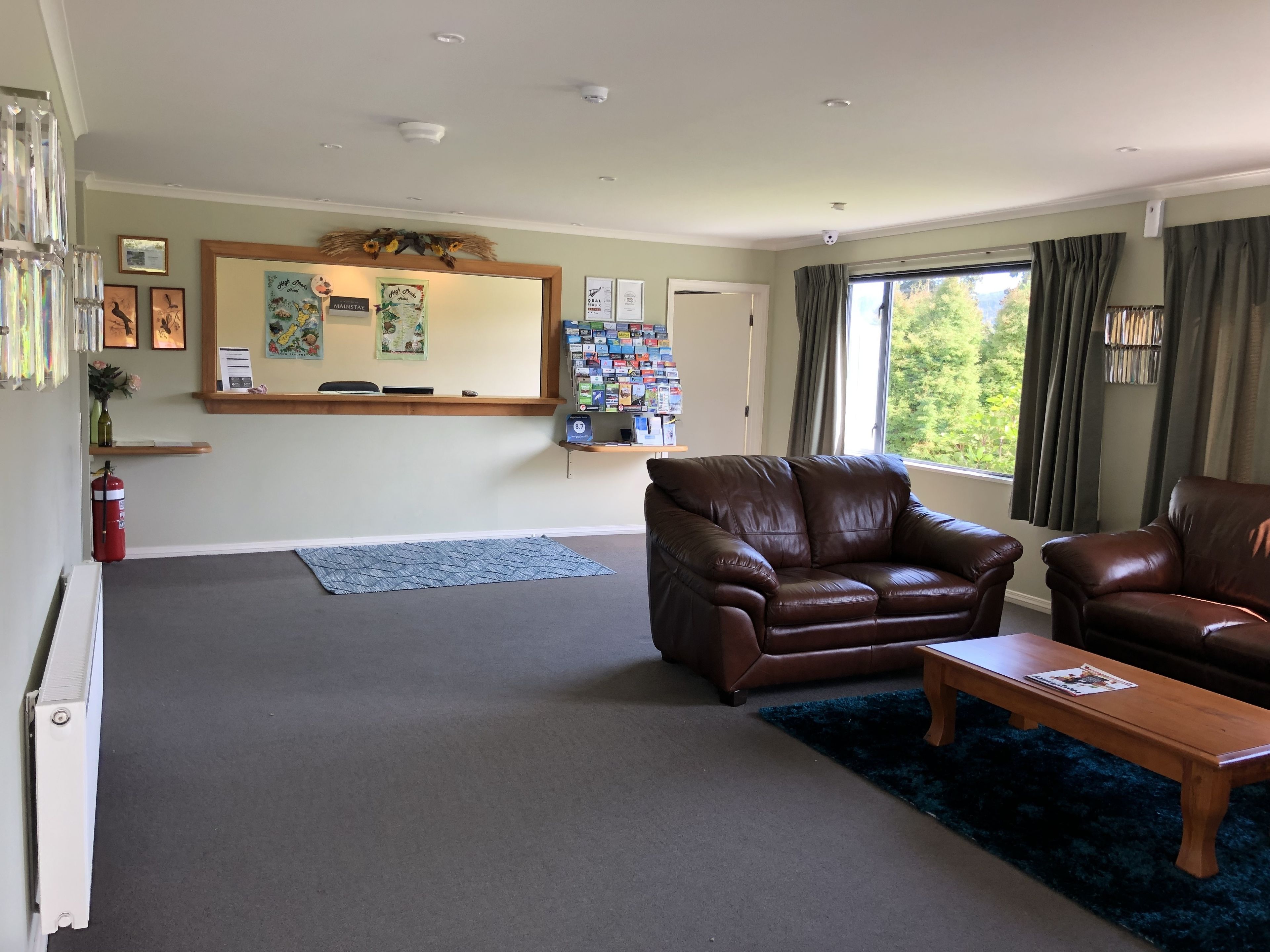 A spacious living room with a brown leather sofa, a wooden coffee table, and a large window with curtains.