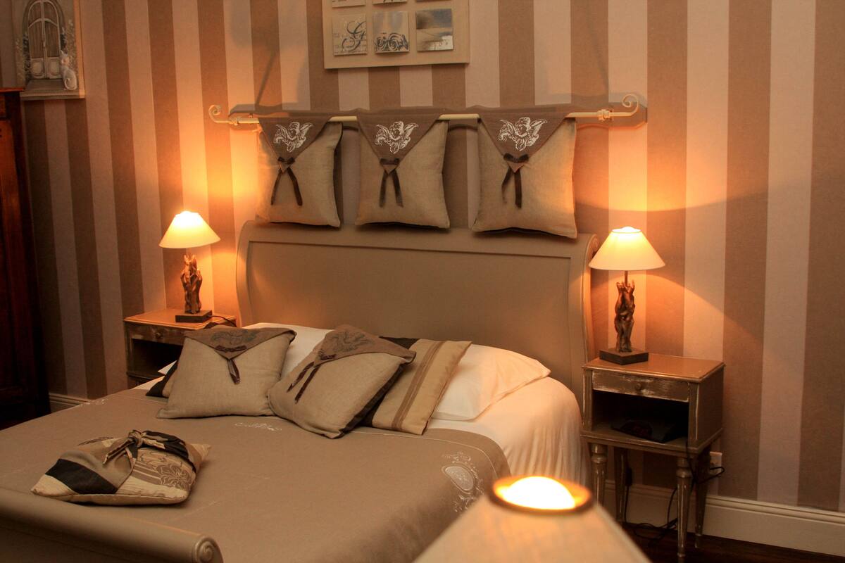 A hotel room with a bed, two bedside tables, and a headboard with decorative pillows.
