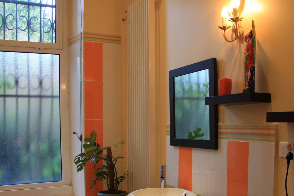 A bathroom with a bathtub, a sink, a mirror, a potted plant, and a window.