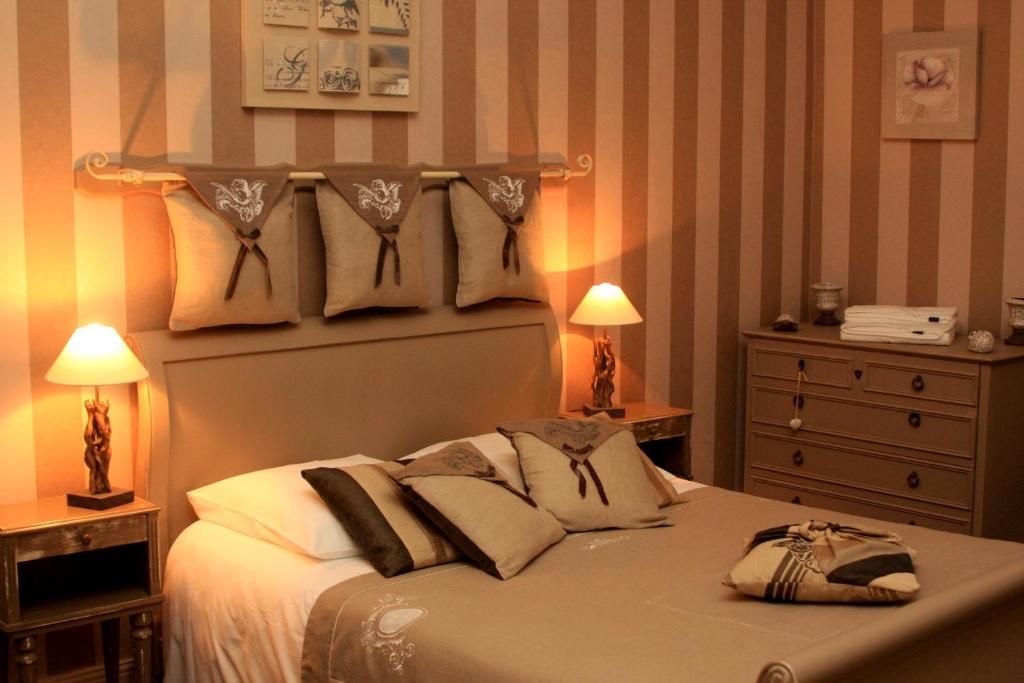 A hotel room with a bed, two bedside tables, a dresser, and a wall with striped wallpaper.