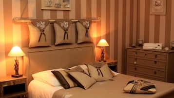 A hotel room with a bed, two bedside tables, a dresser, and a wall with striped wallpaper.