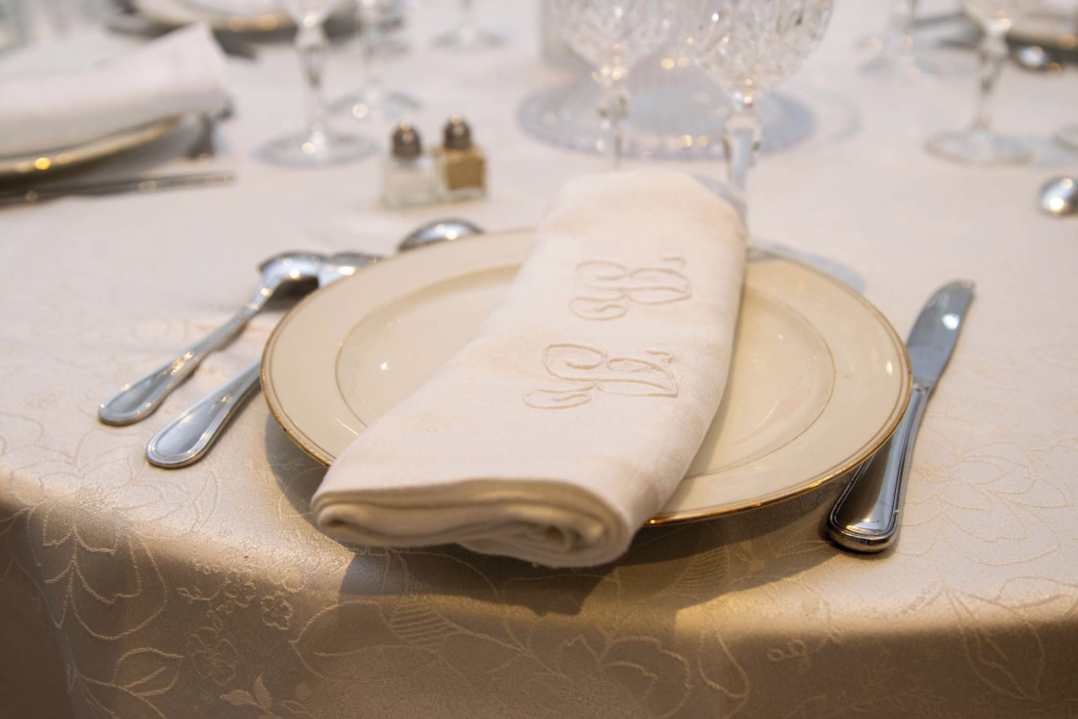 A table set with a folded napkin, a plate, a knife, and a spoon.