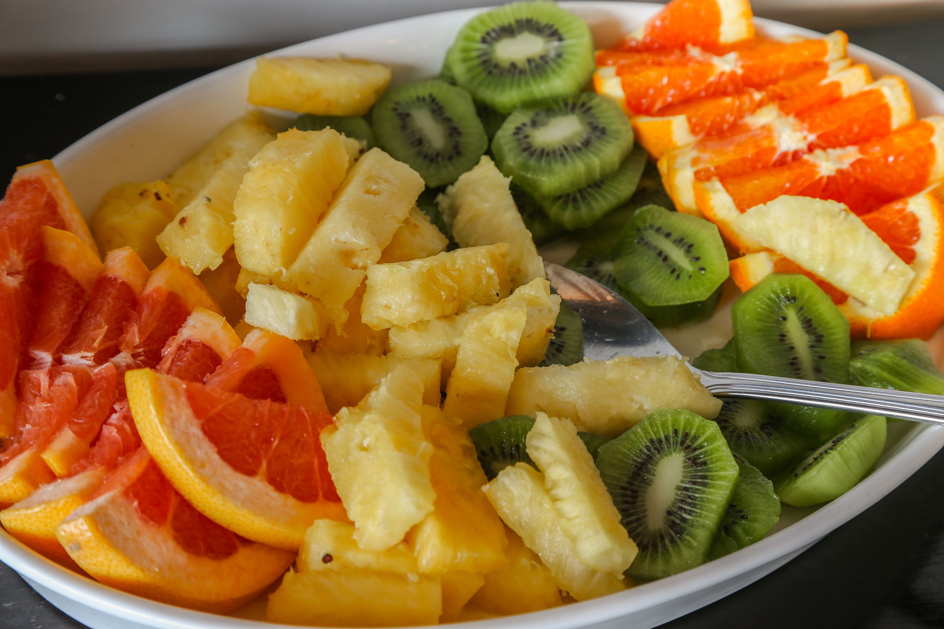 Eine Schüssel mit verschiedenen Früchten, darunter Ananas, Kiwi und Orangenscheiben.