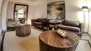 Uma sala de estar moderna com uma mesa de centro redonda de madeira, um sofá marrom e uma grande pintura abstrata na parede.