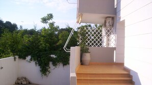 A staircase leading to a balcony with a potted plant on the landing. - Milos Apartments (Kassandra)