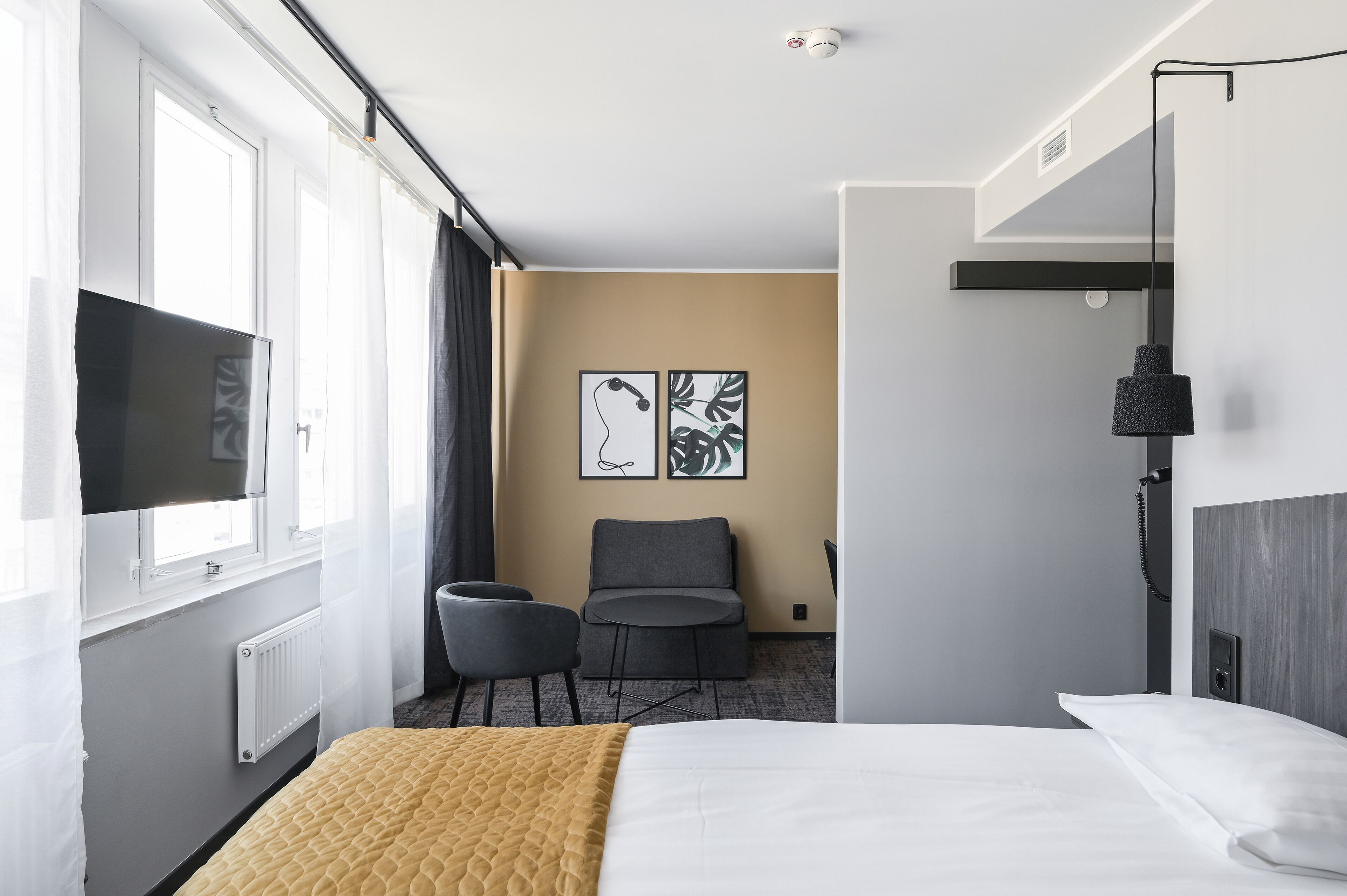 A hotel room with a bed, a TV, a desk, and two chairs.