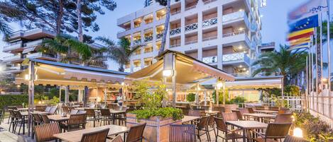 Un hotel con terraza para comer al aire libre, varios pisos y balcones.