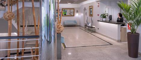 A modern reception area with a reception desk, a seating area, and a staircase with decorative elements.